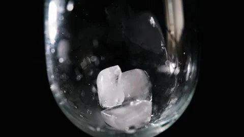 Ice Cube Dropping Into Glass with Water Splashing in Slow Motion Stock Footage 339366107