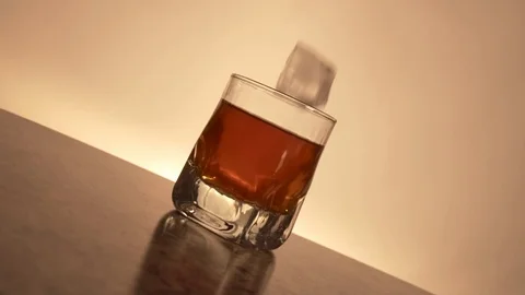 Ice cube drops in whiskey in slow motion Stock Footage 129263922