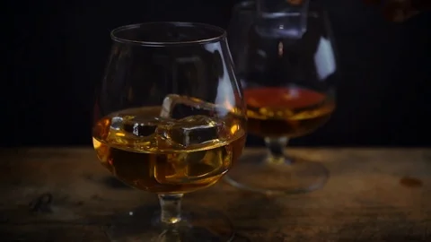 Ice cube falling into cognac \ whiskey glass Stock Footage 125401921