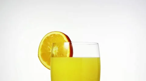 Ice cube falling into a glass of orange juice Stock Footage 8571241