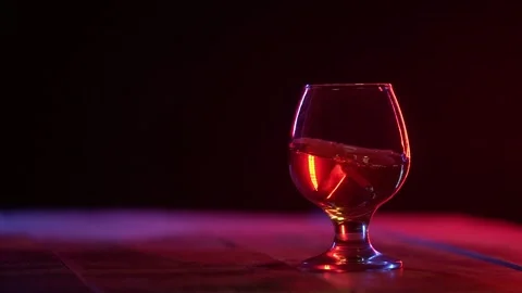 Ice cube falling in the glass of whiskey with splash. Stock Footage 319028370