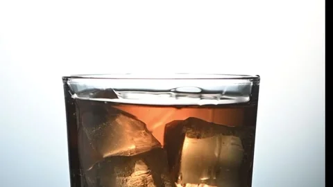 Ice Cube Falling into Whiskey Glass. Slow Motion Splash &amp; Swirl, Premium Drink Stock Footage 325740909