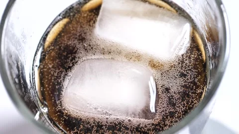 An ice cube falls into a glass of cola Stock Footage 248707704