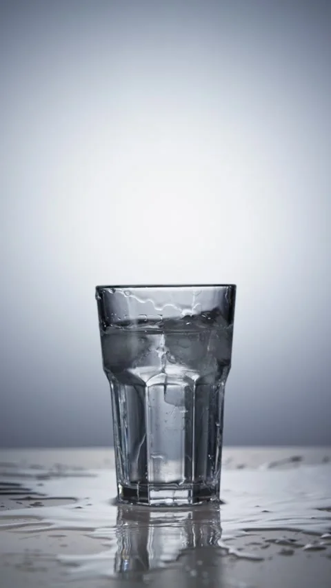 The ice cube fell into the glass and the water splashed instantly Stock Footage 342728284