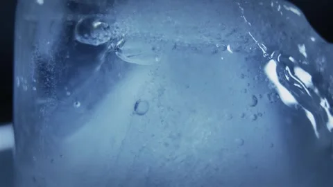 Ice cube in macro view showing frozen bubbles and a cool blue, natural texture Stock Footage 345978972