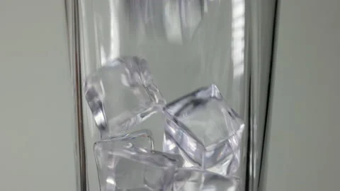 Ice cube pouring dropping into a tall glass bouncing shaking on white background Stock Footage 186896534