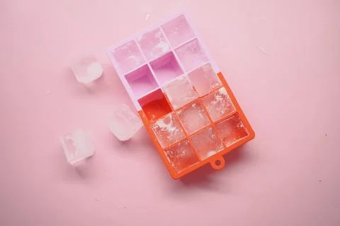 Ice cube tray with ice cubes on a pink background Stock Photos