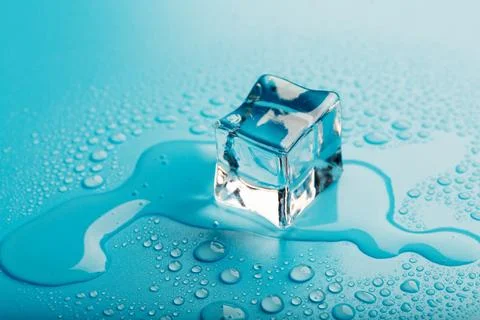 Ice cube with water drops on a blue background. The ice is melting. Stock Photos