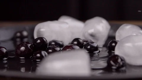 Ice cubes and blueberries fall from above on a black tray Stock Footage 113084228