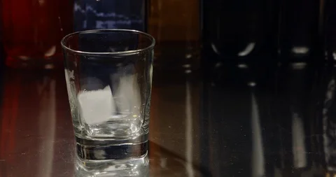 Ice cubes and whiskey are poured into glass Stock Footage 99753786