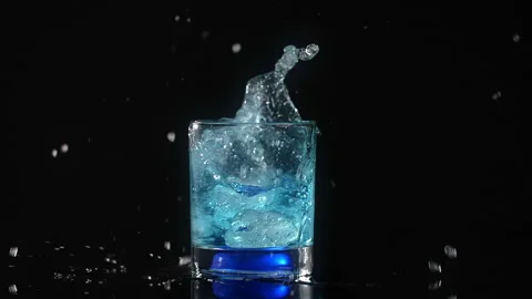 Ice cubes are falling to the cocktail with splash in slow motion on the black Stock Footage 158333870