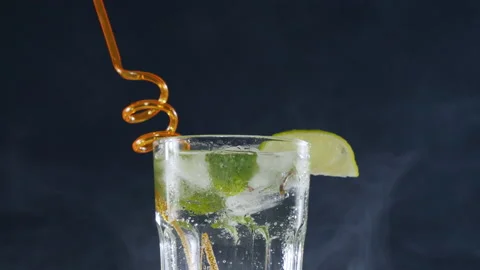 Ice cubes are placed in a cold mojito cocktail with lime and soda Video stock 178478226