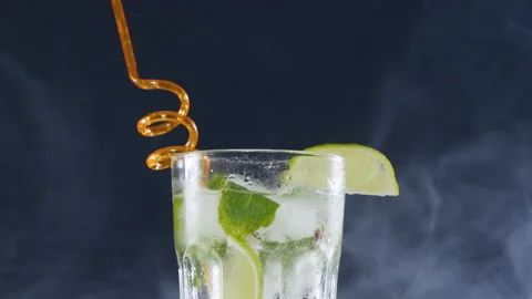 Ice cubes are placed in a cold mojito cocktail with lime and soda Stock Footage 178478741