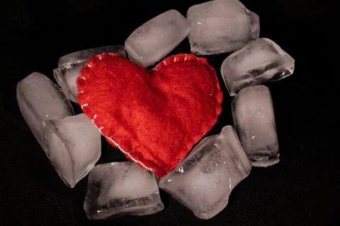 Ice cubes. Black background. Cold. Frozen. Water droplets. Red heart in a bow Stock Photos