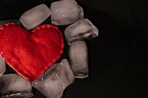 Ice cubes. Black background. Cold. Frozen. Water droplets. Red heart in a bow Stock Photos