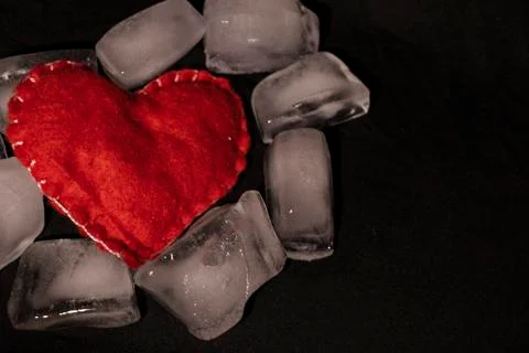 Ice cubes. Black background. Cold. Frozen. Water droplets. Red heart in a bow Stock Photos