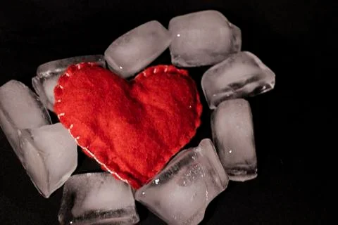Ice cubes. Black background. Cold. Frozen. Water droplets. Red heart in a bow Stock Photos