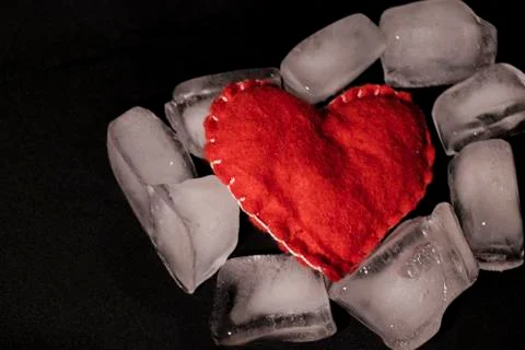 Ice cubes. Black background. Cold. Frozen. Water droplets. Red heart in a bow Stock Photos