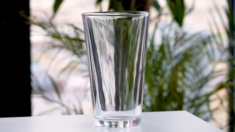 Ice cubes dropped in glass on table Stock Footage 103980235