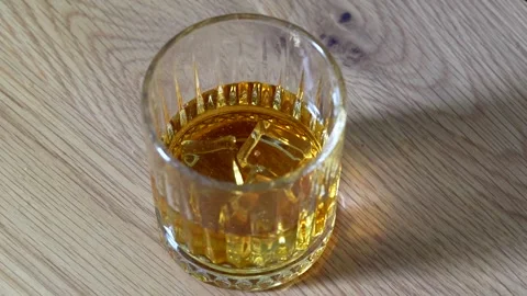 Ice Cubes Dropping into Crystal Glass Full of Whiskey Close Up 4K Splash Stock Footage 332562191