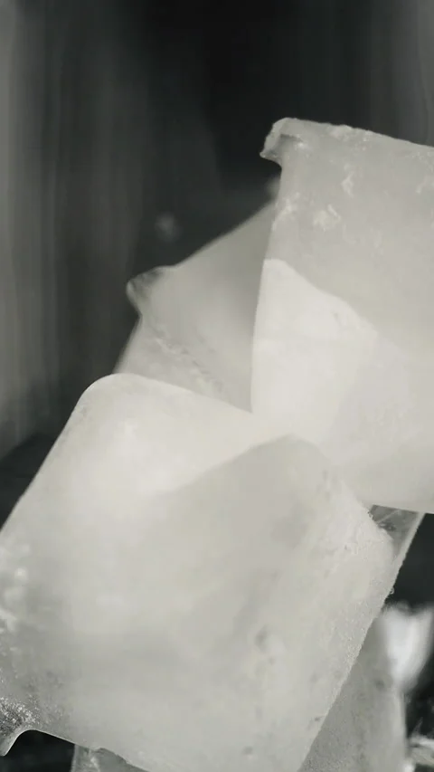 Ice cubes fall into a clear glass. Vertical video. Stock Footage 325705120