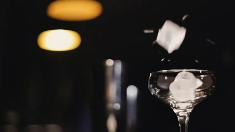 Ice cubes fall into a glass of daisies on a dark background at the bar Stock Footage 144003032