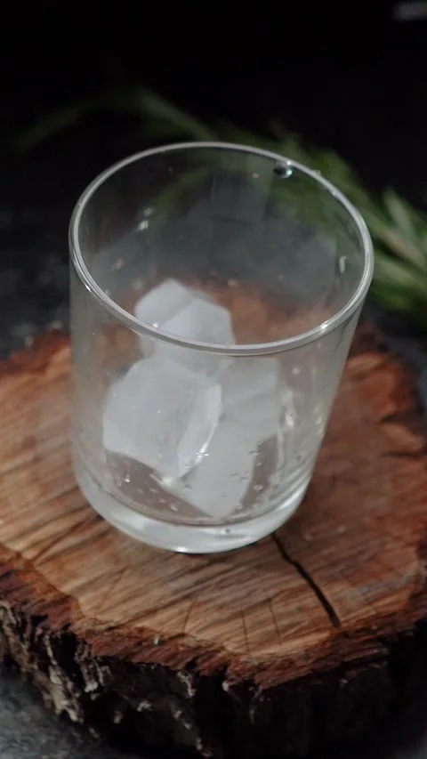 Ice cubes fall into a glass with lime and rosemary and topped with soda. The Stock Footage 279914847