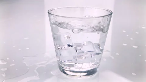 Ice cubes fall into glass of pure water with splash Stock Footage 198709339