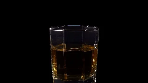 Ice cubes Fall into a glass of Whiskey in Slow Motion on a black Stock Footage 83529186