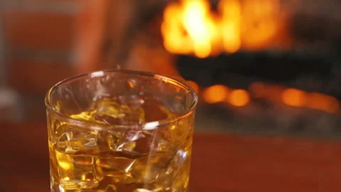 Ice cubes fall into a glass Whiskey. Fireplace With a Flame. Alcoholic Drink. 스톡 동영상 138599856