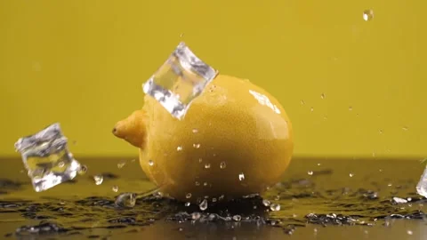 Ice cubes fall on the lemon. Slow motion. Yellow background. Macro mode. Freshne Stock Footage 144334392
