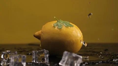 Ice cubes fall on the lemon. Slow motion. Yellow background. Macro mode. Freshne Stock Footage 144334435