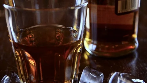 Ice cubes fall into whiskey glass Video stock 102240628