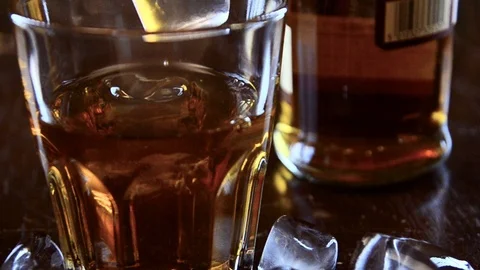 Ice cubes fall into whiskey glass Video stock 102240631
