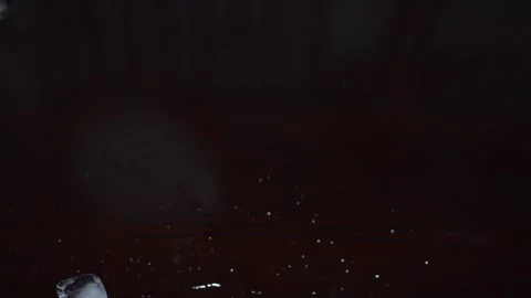 Ice Cubes Falling and Splashing on Dark Wooden Surface 库存影片 347577202