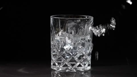Ice cubes falling into a crystal glass of water on black background, closeup Stock Footage 305329812