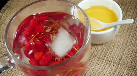 Ice cubes falling into a cup of tea with viburnum Stock Footage 57775485