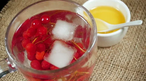 Ice cubes falling into a cup of tea with viburnum Stock Footage 57776166