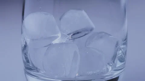Ice cubes falling down into clear glass with focus on clarity and detail of ice Stock Footage 270492459