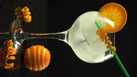 Ice cubes falling in gin orange cocktail with straw, 4k vertical video, close up Stock Footage 155649737