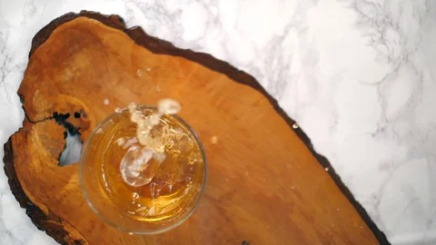 Ice cubes falling into a glass of bourbon whiskey top view slow motion Vidéo 129682503