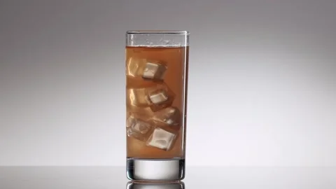 Ice cubes falling into a glass of cold iced tea Stock Footage 342740880