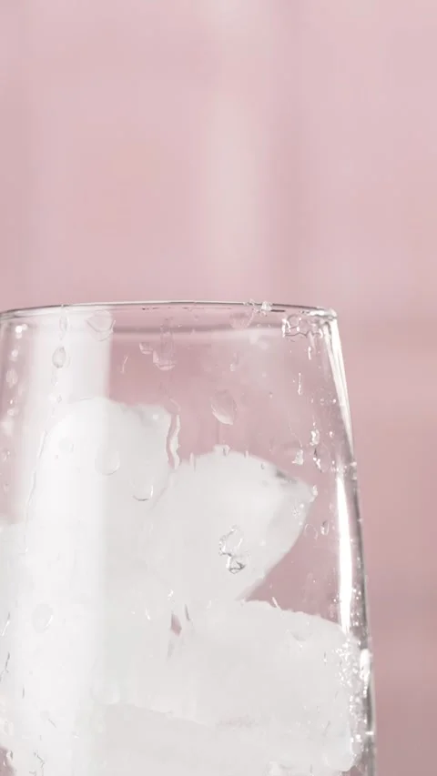Ice Cubes Falling into Glass on a pink background, slow motion. Stock Footage 311004036