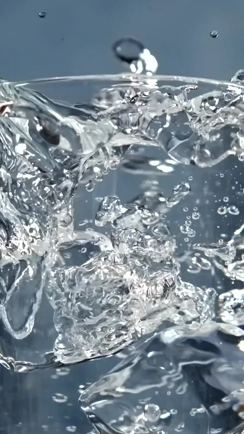 Ice cubes falling into a glass of water with splash in slow motion Stock Footage 345451158
