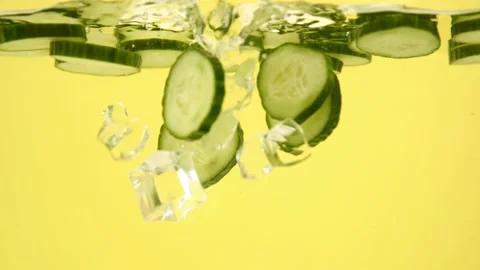 Ice cubes falling into a water with cucumber slices, selective focus 库存影片 153479431