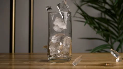 Ice Cubes Falls onto a Table with a Glass of Ice Sitting on It Stock Footage 270406516