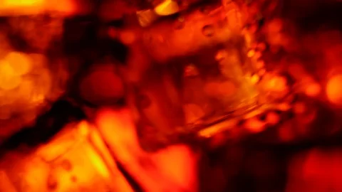 Ice cubes float and spin with bubbles in a glass of cola with brown highlights Video stock 128956872