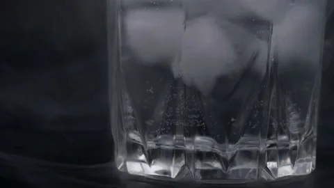 Ice cubes in a glass on a black background. Bubbles in mineral water. Filling Video stock 156869562