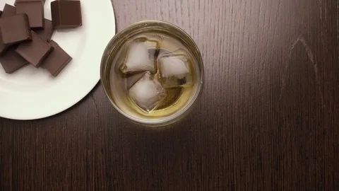 Of ice cubes in a glass of whiskey put on the table. top view Stock Footage 73798505