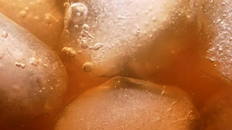 Ice cubes in a golden coffee drink. Bubbles float to the top. An invigorating Stock Footage 152215832